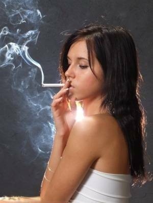 Young brunette smokes a cigarette while wrapped in tight white dress and heels on shefanatics.com