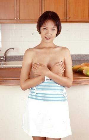 Clothed Asian with tiny tits is posing in the kitchen with spread legs on shefanatics.com