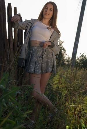 Long haired teen Hrizantema strips to her sneakers by a tree in a field on shefanatics.com