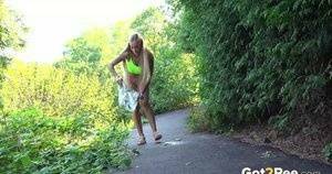 Blonde teen Daisy Lee takes a piss on a paved path through the woods on shefanatics.com