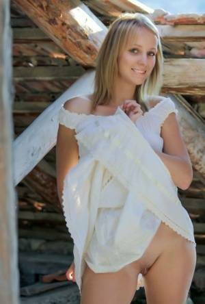 Young blonde Ilona D gets naked in a rustic setting with her boots on on shefanatics.com