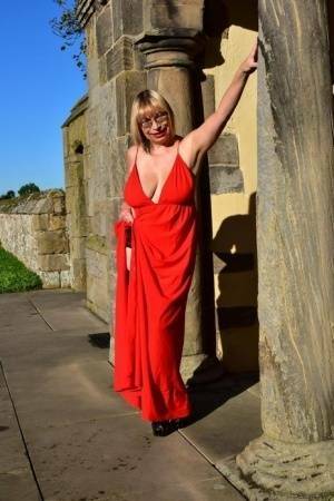 Older blonde Barby Slut doffs a red evening gown to pose nude in hosiery on shefanatics.com