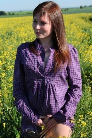 Young redhead gets completely naked in a field of Rapeseed on shefanatics.com