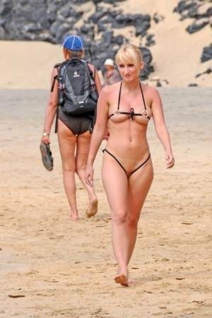 Hot blonde removes a skimpy bikini during a visit to a public beach on shefanatics.com